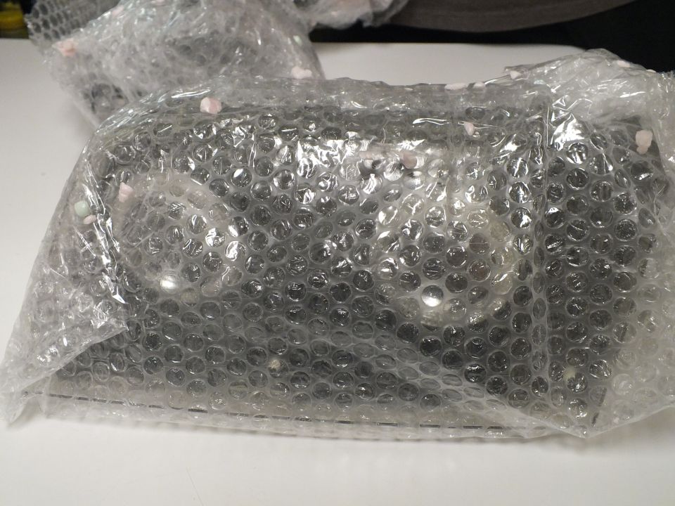 Clear automotive lenses sealed in bubble-wrap bags on a desk