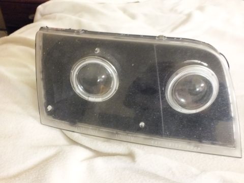 2003 Ford Crown Victoria - Single black-housing dual projector and halo headlight lens laid on a soft cloth.