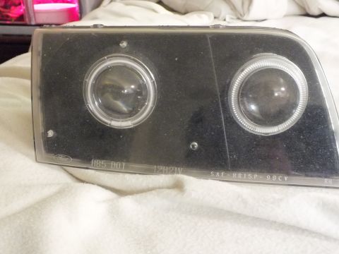 2003 Ford Crown Victoria - Black dual-projector headlight with Ford oval and HB5 DOT 98CV markings on the lens.