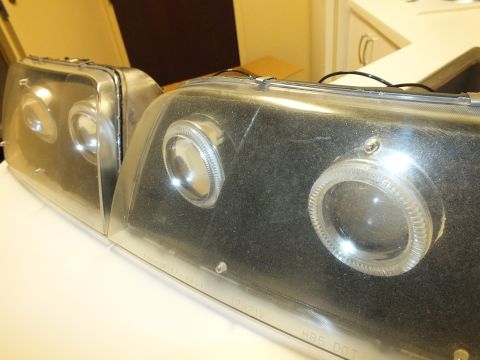 2003 Ford Crown Victoria - Smoked black projector headlights with halo rings angled together on a tabletop.