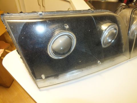 2003 Ford Crown Victoria - Smoked projector headlight lens showing a Ford oval and HB5 DOT text along the bottom edge.