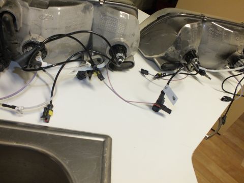 2003 Ford Crown Victoria - Two aluminum headlight reflectors with HID wiring and Ford oval marks on a kitchen counter.