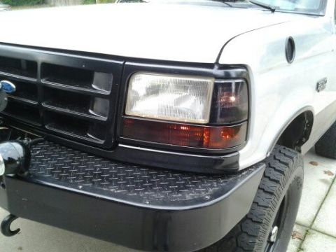 1996 Ford Bronco - Close-up of the front grille and headlight assembly on a white Ford F-Series truck.