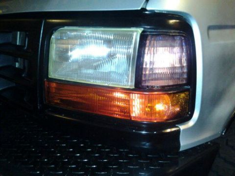 1996 Ford Bronco - Close-up of the front end of a silver 1992 Ford Bronco, showing the headlights and grille.