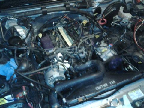 1996 Ford Bronco - A cluttered engine bay with many wires and hoses is visible, with a caution fan warning.