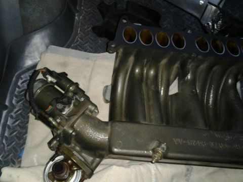 1996 Ford Bronco - Close-up of an engine intake manifold with visible part numbers and a SuperMotors watermark.