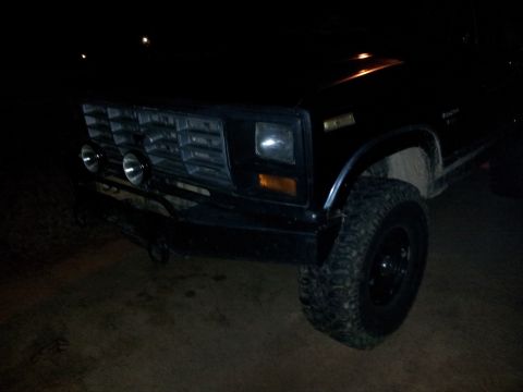 1986 Ford Bronco - Front view of a 1986 Ford Bronco at night, showing its grille and headlights.