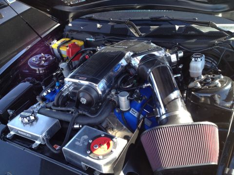 2013 Ford Mustang - The engine bay features a prominent supercharger and custom components, suggesting performance modifications.