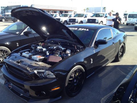 2013 Ford Mustang - A black Ford Mustang is parked with its hood open, revealing the engine and custom wheels.