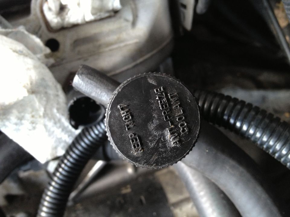 Close-up of a black coolant reservoir cap with text 'KEEP TIGHT ANTI-FREEZE COOLANT'