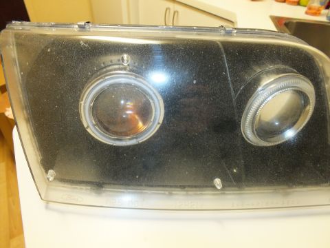 2003 Ford Crown Victoria - Smoked black dual-projector halo headlight resting on an appliance with HB5 DOT text.