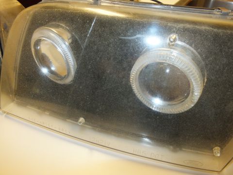 2003 Ford Crown Victoria - Detail of a smoked projector headlight lens with halo rings and SAE-HR15P 98CV text.