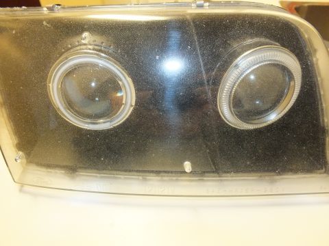 2003 Ford Crown Victoria - Smoked projector halo headlight lens marked HB5 DOT and SAE-HR15P-98CV near a Ford oval.