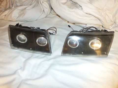 2003 Ford Crown Victoria - Matched pair of aftermarket dual-projector headlamps showing angel-eye halo rings and connector harnesses.