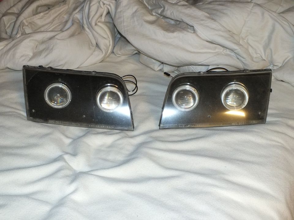 Pair of dual-projector halo headlights with lit halo rings and visible DOT etched markings