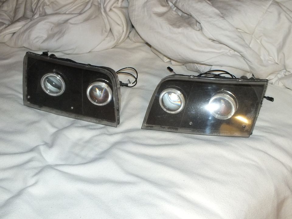 Left and right dual-projector halo headlight units with smoked lenses angled on white sheet
