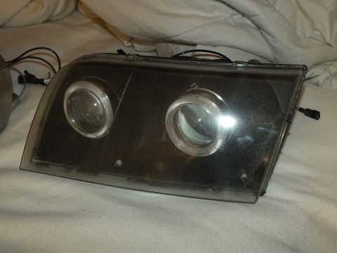 2003 Ford Crown Victoria - One retrofit headlamp showing twin projector lenses and halo rings under lens glare.