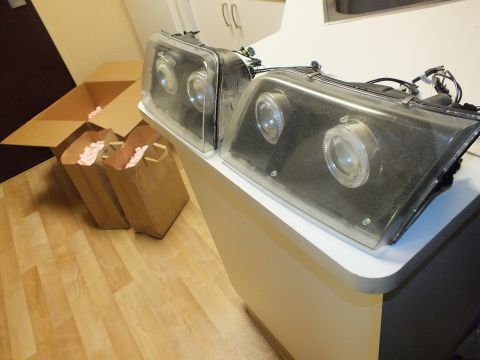 2003 Ford Crown Victoria - Pair of custom headlamps with hazed projector lenses placed on a counter beside shipping boxes.