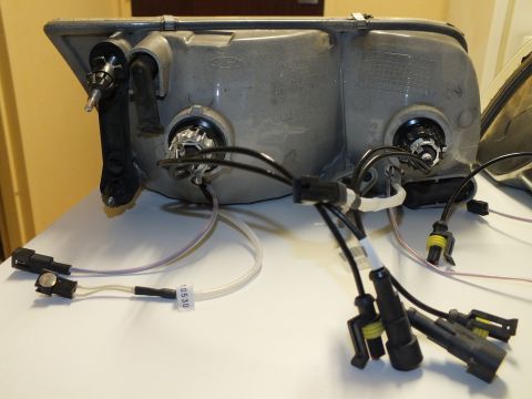 2003 Ford Crown Victoria - Backside of a headlamp housing with twin bulb sockets, ballast wiring and a Ford oval molded in.