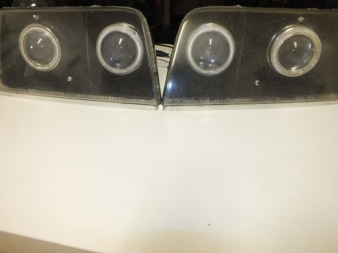 2003 Ford Crown Victoria - Custom headlamp pair lens-side up showing twin projectors, halo rings and lens part text.
