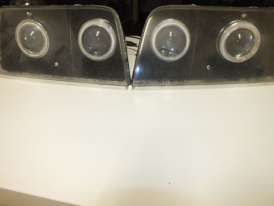 Pair of dual-projector halo headlights face-up on white surface with etched DOT markings