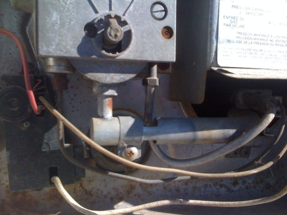 Burner tube, thermocouple and gas valve detail inside an RV propane water heater bay