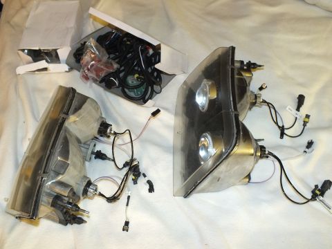 2003 Ford Crown Victoria - Retrofit headlight assemblies showing dual projector lenses beside a box of coiled wiring and plug pigtails.