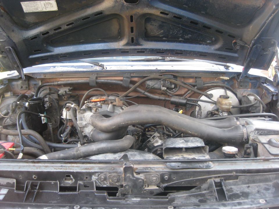 Engine bay of a 1994 Ford Bronco with the hood open, showing the engine components and wiring