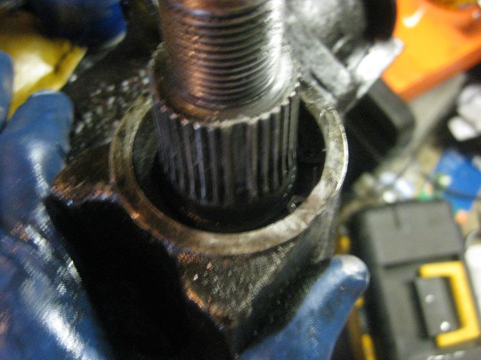 Close-up of a splined shaft inside a steering gear housing, held by a gloved hand