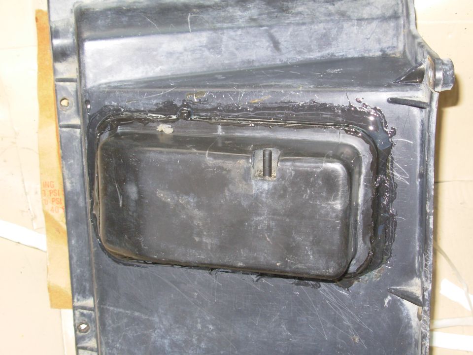 Black plastic transmission or transfer case pan with old sealant residue around the gasket flange