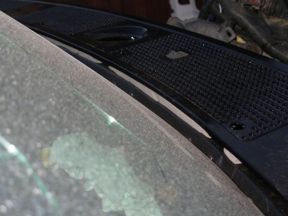 Dusty windshield edge and black perforated cowl vent grille