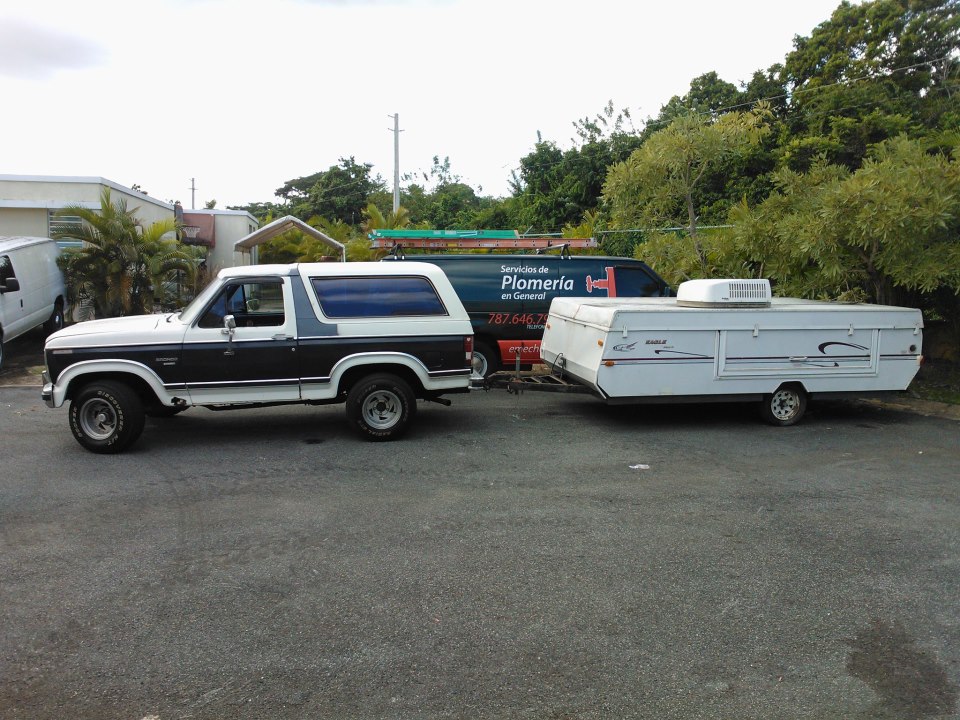 Two-tone white and dark brown Ford Bronco towing a white pop-up camper