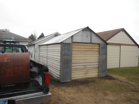 1966 Ford Bronco - A pickup truck is parked next to a detached garage on a cloudy day.