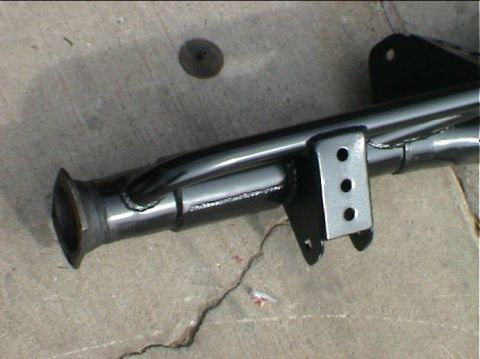 1979 Ford Bronco - A black painted rear axle housing with welded brackets is shown resting on a concrete floor.