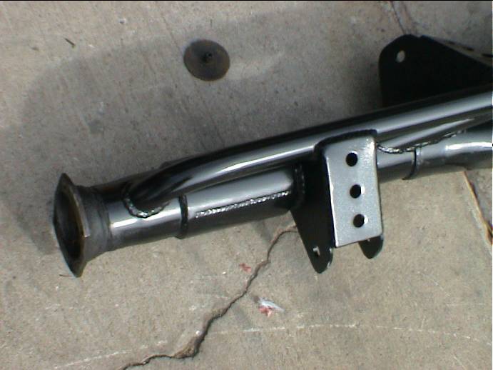 End of black-painted axle housing with welded spring perch and three-hole shock bracket