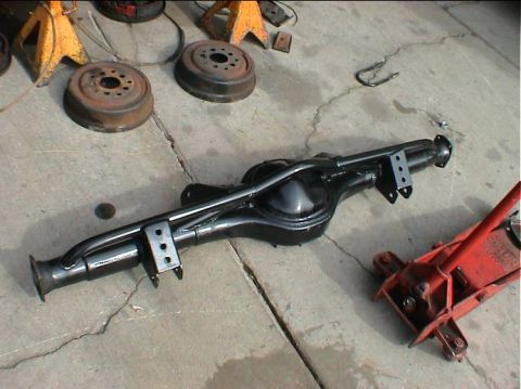 1979 Ford Bronco - A black rear axle assembly is shown on a concrete surface, accompanied by jack stands and brake drums.