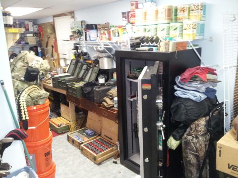 1986 Ford Bronco - A room is filled with various items including a large open safe, shelves stocked with goods, and numerous storage boxes.