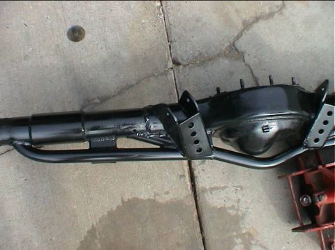 1979 Ford Bronco - A black painted rear axle assembly with suspension brackets is shown resting on a concrete surface.