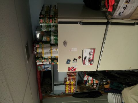 1986 Ford Bronco - Canned goods are stacked high on shelves next to a refrigerator in what appears to be a pantry or storage area.