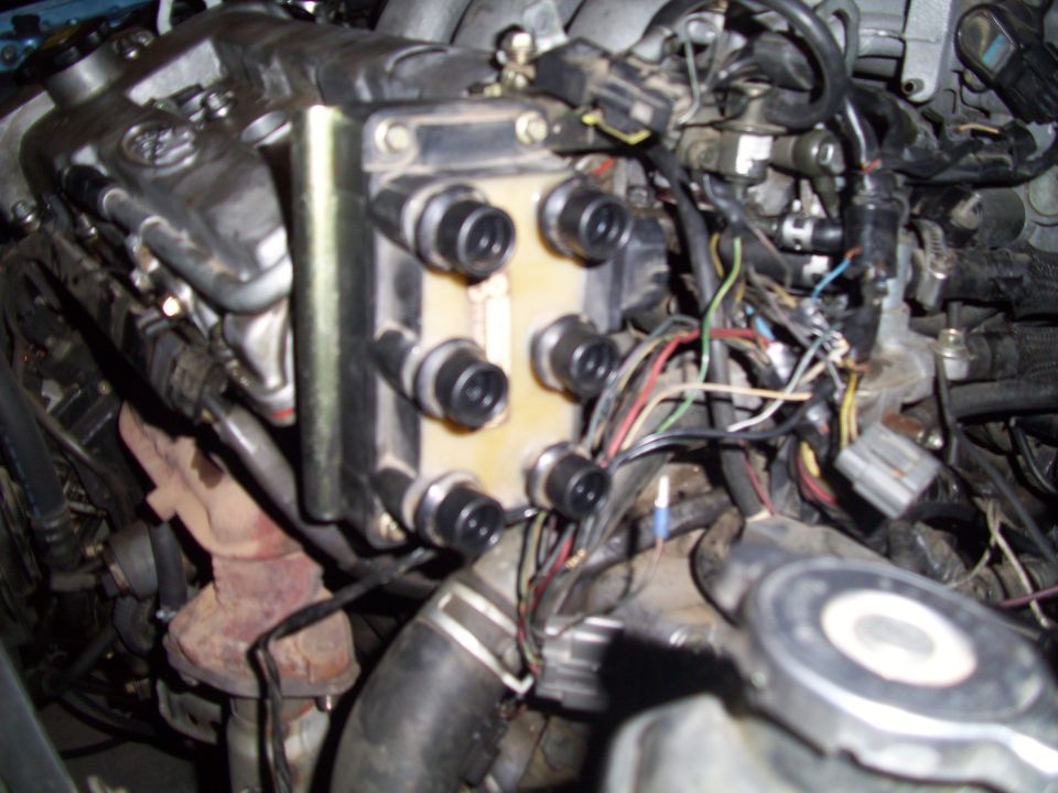 Engine ignition coil pack with multiple spark plug wires connected, showing engine components and wiring harness