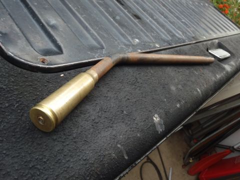 1978 Ford Bronco - A tool made from a brass casing and bent metal pipe rests on a dark, textured surface.