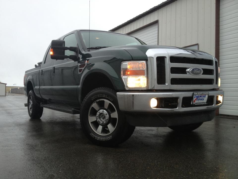 Dark green 2008 Ford F-350 pickup truck, front 3/4 view, chrome grille, wet asphalt