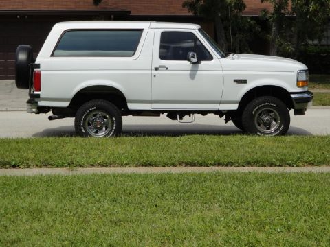 1994 Ford Bronco - Side view of a white 1994 Ford Bronco with a spare tire mounted on the rear.