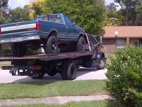 1994 Ford Bronco - A Ford pickup truck is being transported on a flatbed tow truck.