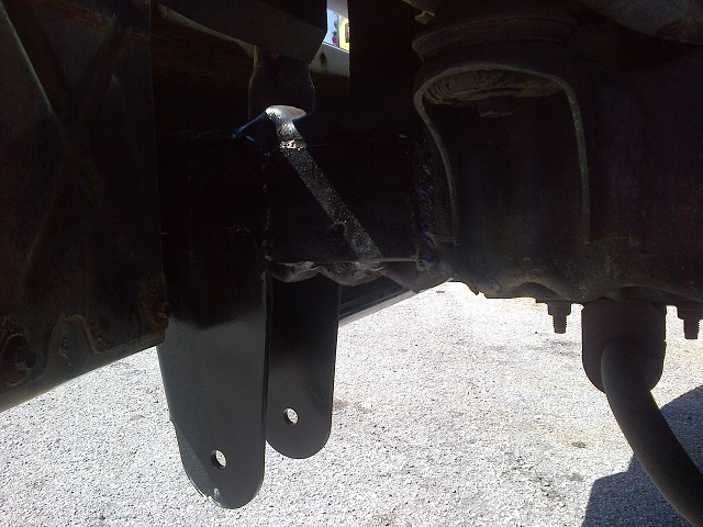 Black painted suspension brackets and frame components with visible bolts and a shock absorber