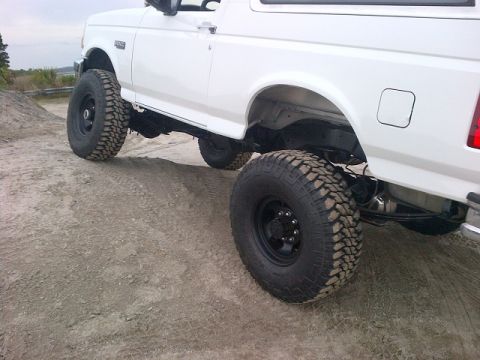 1994 Ford Bronco - This lifted white Ford Bronco features aggressive off-road tires and suspension modifications.