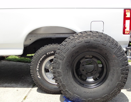 White SUV rear fender with two off-road tires, one with 'All-Terrain T/A' text