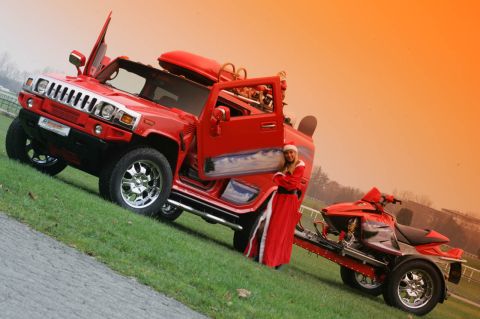 1991 Ford LTD Crown Victoria - A festive red Hummer H2 is parked on a grassy slope with a woman in a Santa suit and a trailer carrying an ATV.