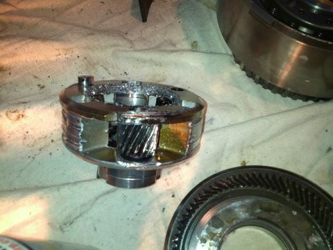 1995 Ford Bronco - A damaged planetary gear set from a transmission, showing broken teeth and significant metal shavings, indicating internal failure.