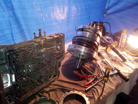 1995 Ford Bronco - Automatic transmission components are laid out on a table, alongside various tools, suggesting a repair or rebuild process.